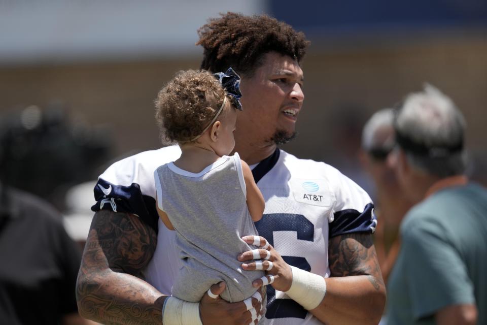 Former Chicago Bears and Dallas Cowboys tackle Aviante Collins (76) holds his daughter during training camp.