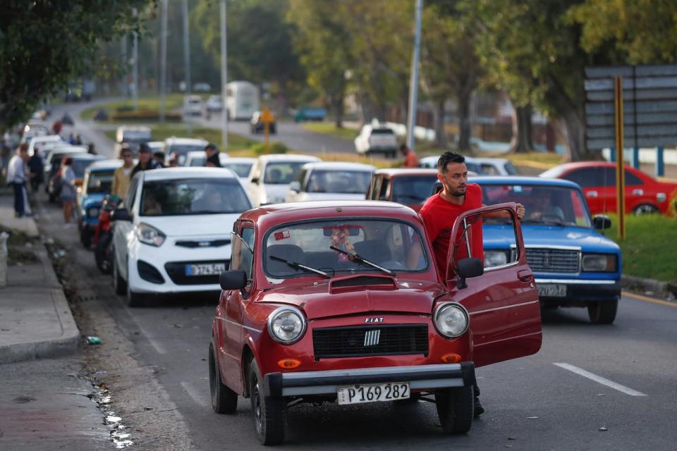 A man pushes his car while queuing up with a line of motorists at a Havana gas station on Tuesday. Cuba's government says it will be raising the price of gasoline roughly fivefold at the start of February. (Yander Zamora/Reuters - image credit)