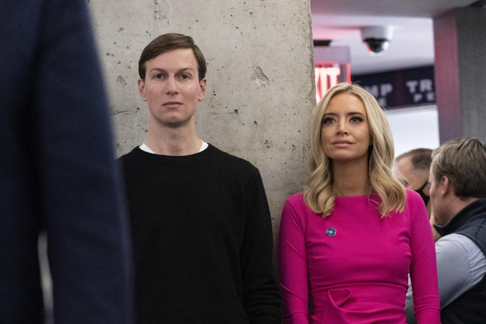 FILE - White House senior adviser Jared Kushner, left, and White House press secretary Kayleigh McEnany listen as President Donald Trump speaks at the Trump campaign headquarters on Election Day, Nov. 3, 2020, in Arlington, Va. At least 13 former Trump administration officials, including Kushner and McEnany, violated the law by intermingling campaigning with their official government duties. That's according to a new federal investigation released Tuesday. (AP Photo/Alex Brandon, File)