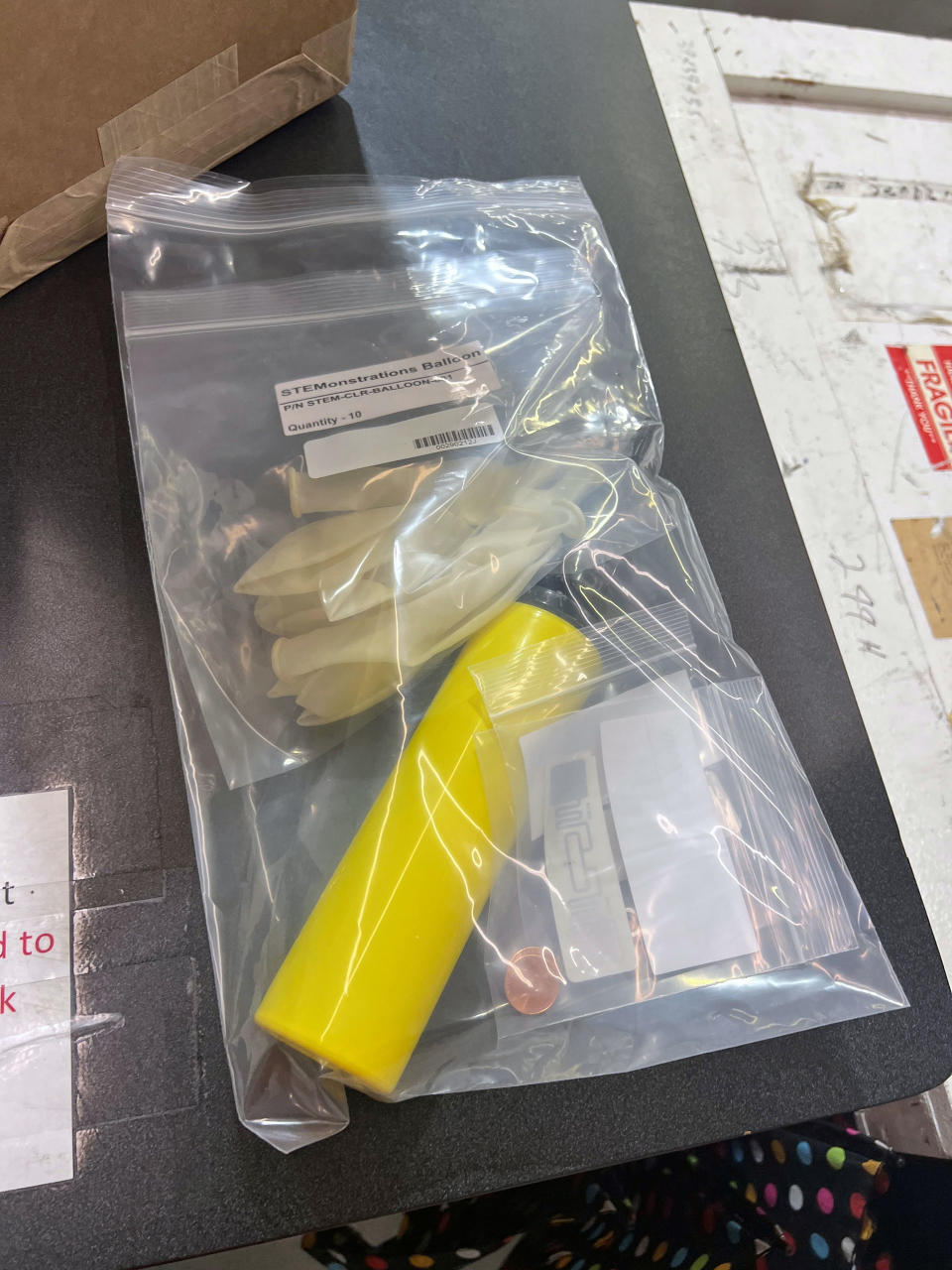 a plastic bag containing some cents and a yellow cylinder rests on a table