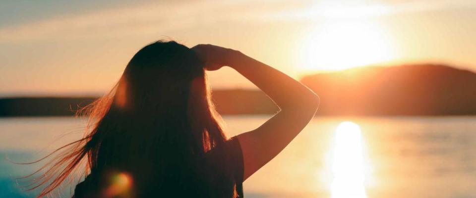 Happy Hopeful Woman Looking at the Sunset by the Sea. Silhouette of a dreamer girl looking hopeful at the horizon