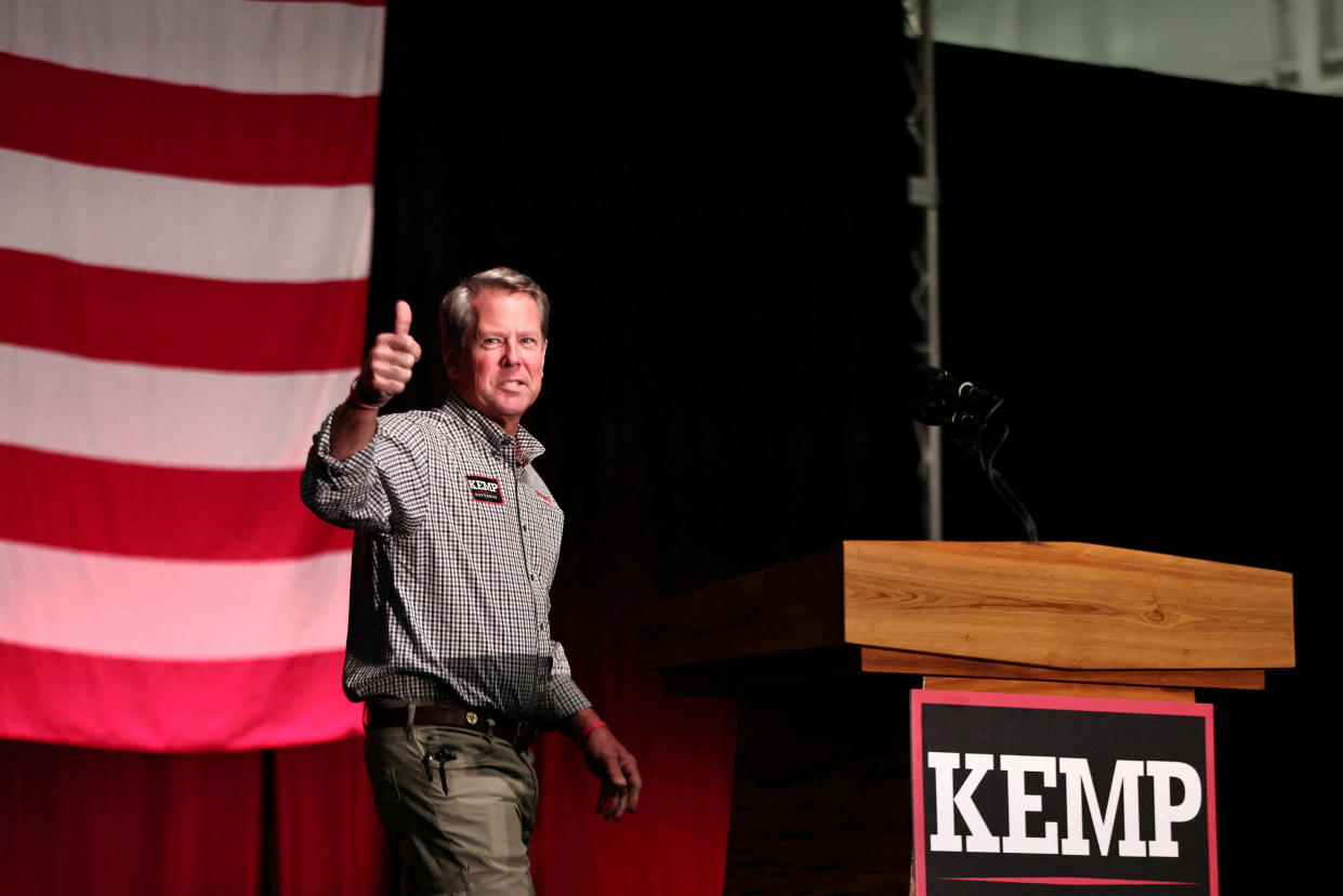 Gov. Brian Kemp gives a thumbs up sign as he walks to a podium.