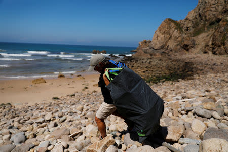 Miguel Lacerda, 62, carries a bag with trash as he leaves a beach at the coast near Sintra, Portugal May 22, 2019. REUTERS/Rafael Marchante