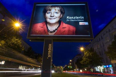 A long exposure photograph shows an election campaign poster of German Chancellor and conservative Christian Democratic Union (CDU) leader Angela Merkel in Berlin, September 12, 2013. EREUTERS/Thomas Peter