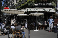 People sit on the Cafe de Flore terrace in Paris, Tuesday, June 2, 2020. Local Parisians are savoring their cafe au lait and croissants at the Left Bank's famed Cafe de Flore, or on the cobbled streets of the ancient Le Marais for the first time in almost three months. As virus confinement measures were relaxed Tuesday, cafes around France were allowed to reopen. (AP Photo/Christophe Ena)