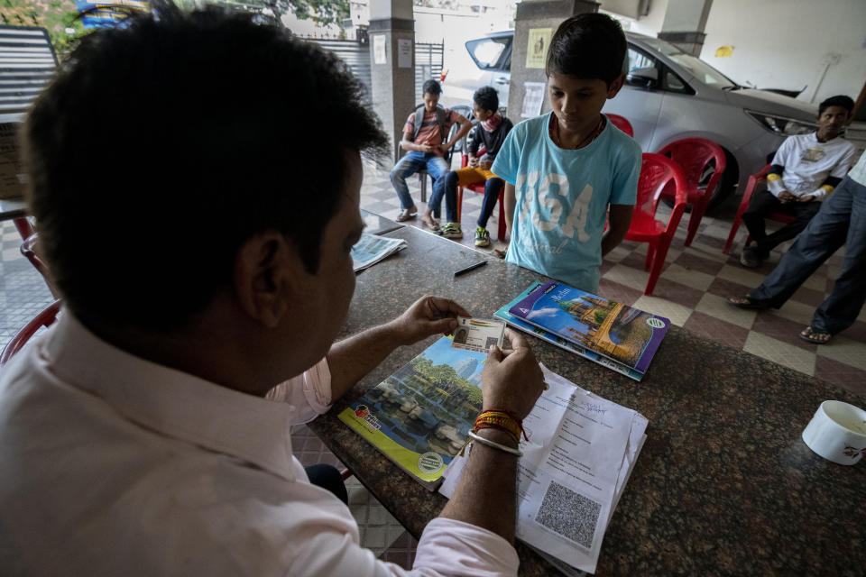 A man checks identity card of a boy who came to receive vaccine for COVID-19 at a private vaccination center in Gauhati, India, Sunday, April 10, 2022. (AP Photo/Anupam Nath)