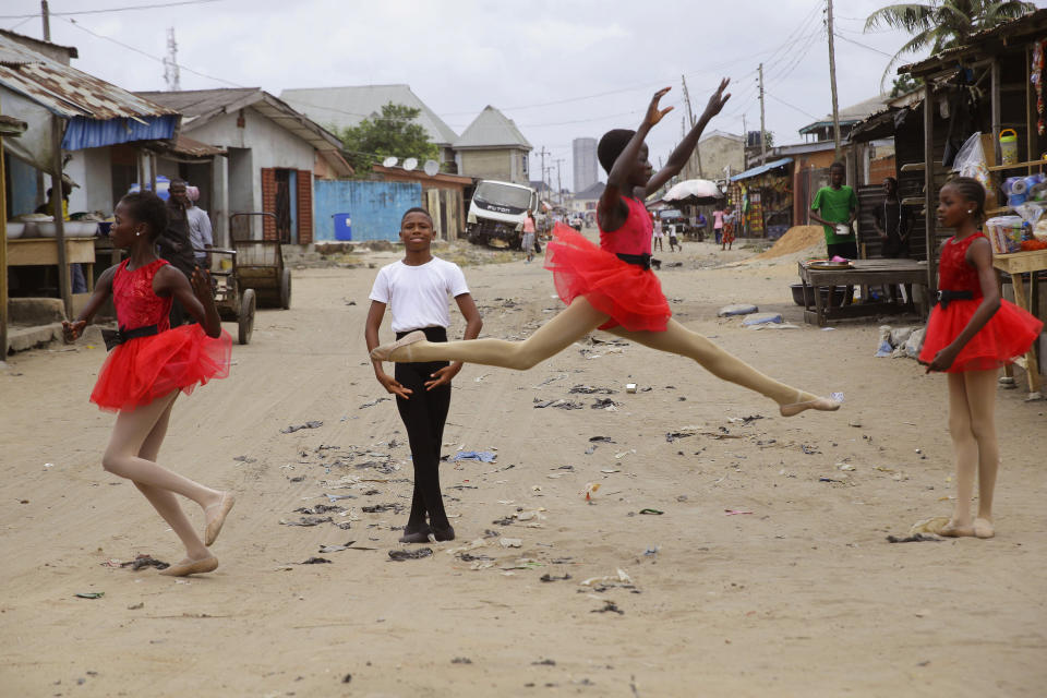 Ballet student Anthony Mmesoma Madu, center, stands in position as fellow dancers perform in the street in Lagos, Nigeria on Aug. 18, 2020. Cellphone video showing the 11-year-old Madu dancing barefoot in the rain went viral on social media. Madu’s practice dance session was so impressive that it earned him a ballet scholarship with the American Ballet Theater in the U.S. (AP Photo/Sunday Alamba)