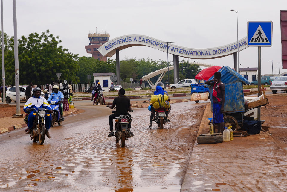 Motociclistas circulan por la entrada al aeropuerto de Niamey, Níger, el 8 de agosto de 2023. (AP Foto/Sam Mednick)