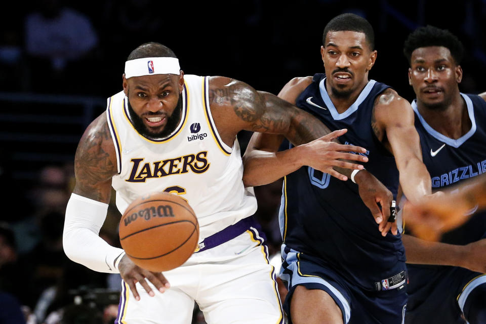 Los Angeles Lakers forward LeBron James, left, and Memphis Grizzlies guard De'Anthony Melton chase the ball during the second half of an NBA basketball game in Los Angeles, Sunday, Oct. 24, 2021. The Lakers won 121-118. (AP Photo/Ringo H.W. Chiu)