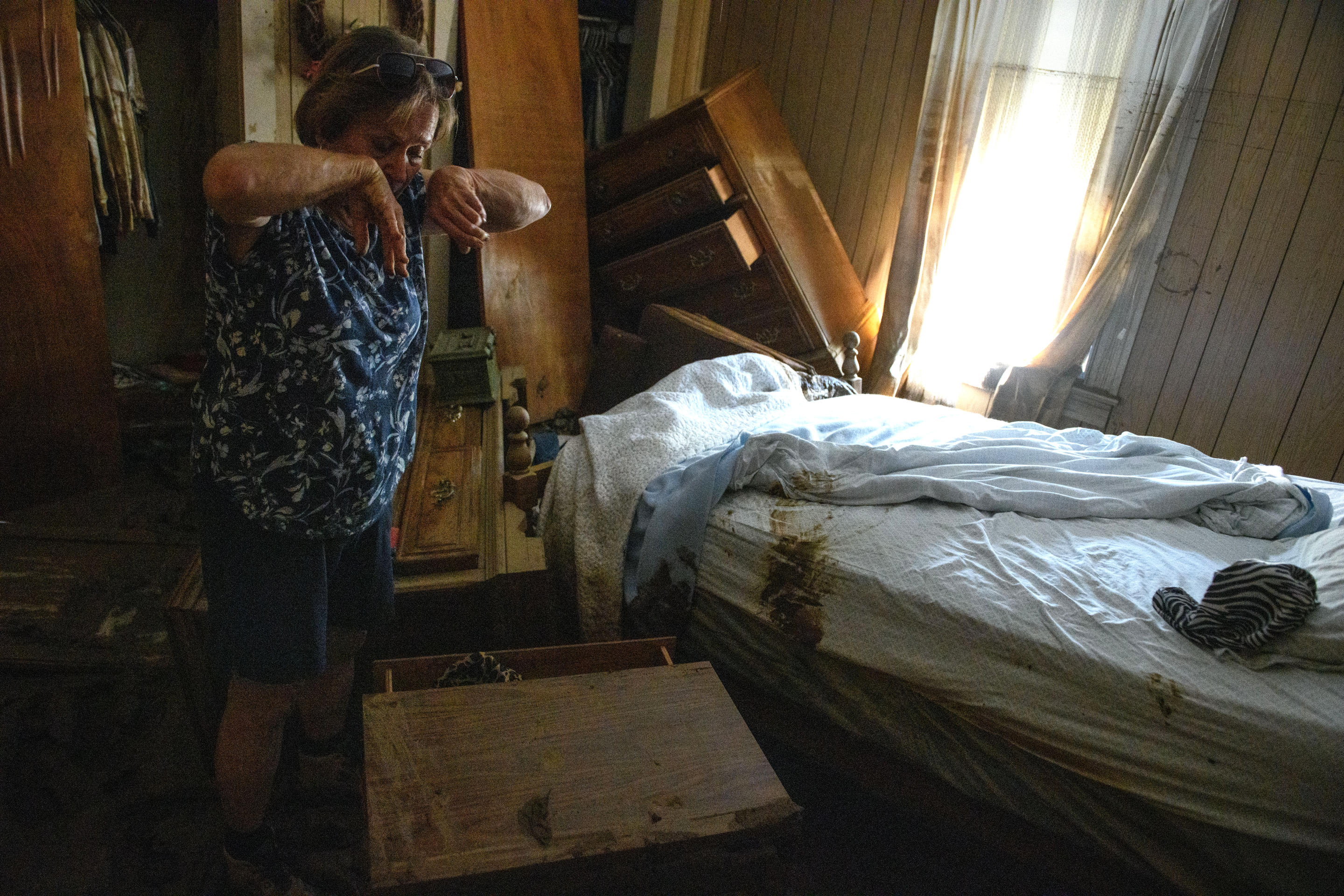 Janice Whitley wipes her face as she searches for valuables in her 93-year-old mother's bedroom.