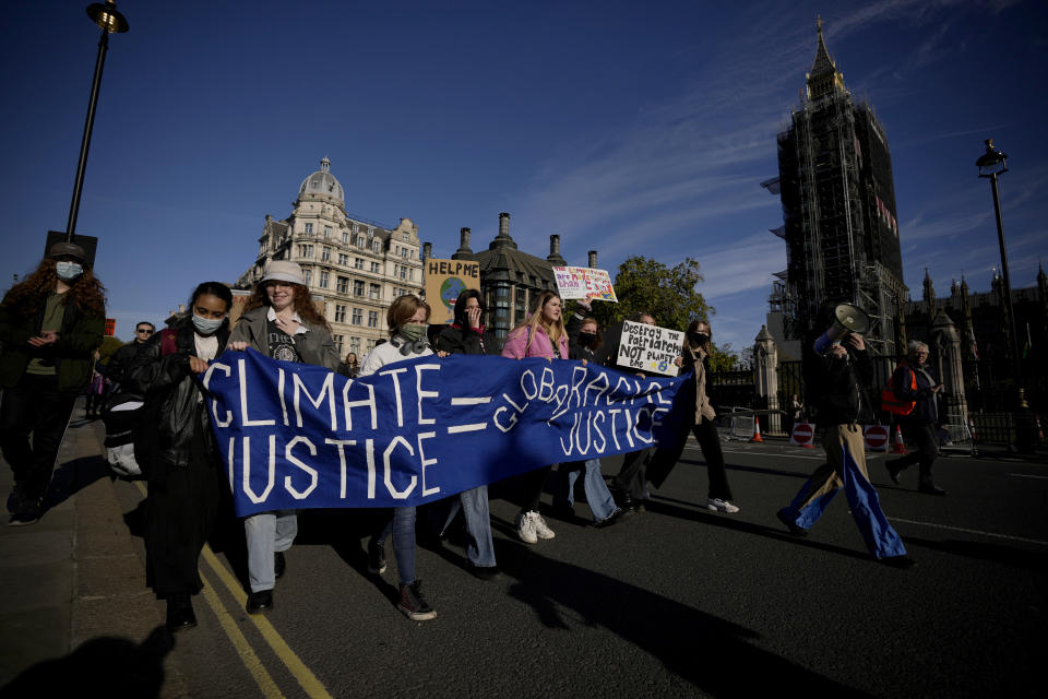 Young climate campaigners march past the scaffolded Elizabeth Tower, known as Big Ben, and the Houses of Parliament as they take part in a UK Student Climate Network (UKSCN) protest, in central London, Friday, Nov. 5, 2021. The London protest was held Friday to coincide with a climate protest in Glasgow at the COP26 U.N. Climate Summit. (AP Photo/Matt Dunham)