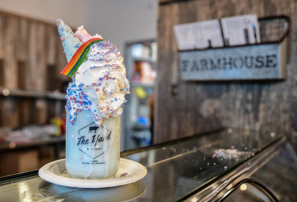 The Yard's Unicorn milkshake features cotton candy ice cream with a marshmallow cream-coated jar dipped in sprinkles and topped with whipped cream, a unicorn cone made in-house, a rainbow candy stripe and cotton candy.