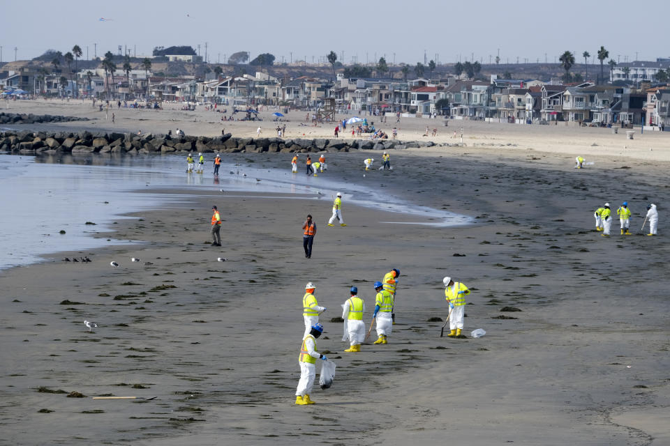 Workers in protective suits clean the contaminated beach after an oil spill, Wednesday, Oct. 6, 2021 in Newport Beach, Calif. A major oil spill off the coast of Southern California fouled popular beaches and killed wildlife while crews scrambled Sunday, to contain the crude before it spread further into protected wetlands. (AP Photo/Ringo H.W. Chiu)