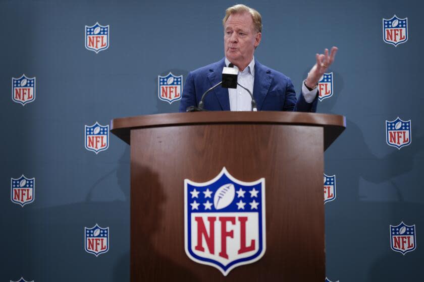 NFL commissioner Roger Goodell stands behind a podium and responds to questions during a news conference