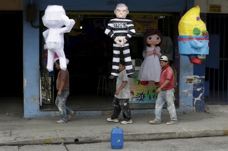 People walk past a pinata (C) representing former Guatemala's President Otto Perez wearing a jail uniform outside a pinatas store in downtown Guatemala City, September 4, 2015. REUTERS/Jorge Dan Lopez