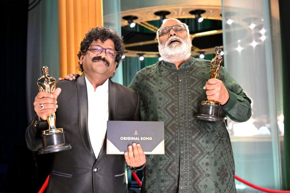 chandrabose and m m keeravani smile while holding academy awards and an envelope that says original song on it