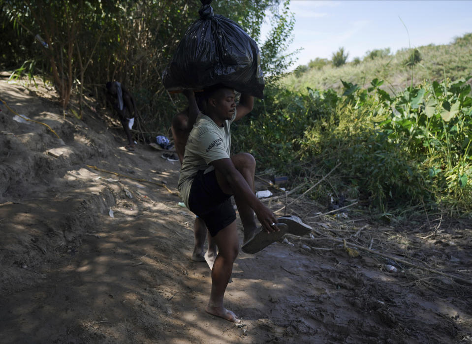 A migrant from Haiti removes his sandals before crossing the Rio Grande to Del Rio, Texas, from Ciudad Acuña, Mexico, Wednesday, Sept. 22, 2021. (AP Photo/Fernando Llano)