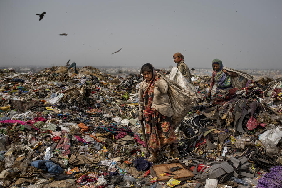 Trash pickers look for recyclable waste at the Bhalswa landfill on the outskirts of New Delhi, India, Wednesday, March 10, 2021. An estimated 20 million people around the world help keep cities clean by scavenging through landfills and dumps. Experts say these trash pickers, who sometimes toil alongside paid municipal sanitation workers, provide a vital service, yet they usually are not on a priority list for coronavirus vaccines. (AP Photo/Altaf Qadri)