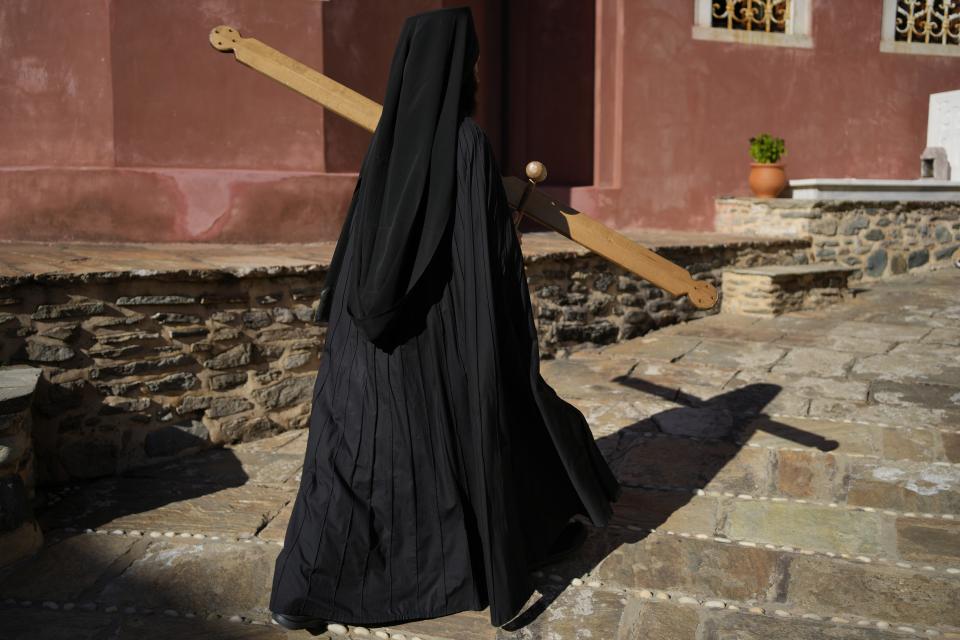 A monk uses a mallet and plank to summon monks and visitors to the afternoon prayers at the Pantokrator Monastery in the Mount Athos, northern Greece, on Thursday, Oct. 13, 2022. Deep inside a medieval fortified monastery in the Mount Athos monastic community, researchers are for the first time tapping a virtually unknown treasure: thousands of Ottoman-era manuscripts that include the oldest of their kind in the world. (AP Photo/Thanassis Stavrakis)