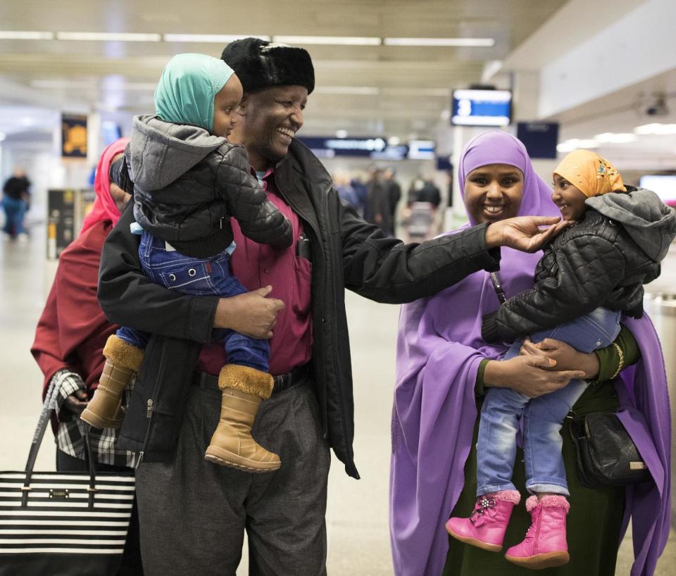 Mohamed lye, carrying his 2-year old daughter Nafiso, plays with his 4-year-old daughter Nimo, carried by family friend Abdinasir Abdulahi, at Minneapolis–Saint Paul International Airport near Bloomington, Minn., after arriving from Amsterdam on Sunday, Feb. 5, 2017. His wife Saido Ahmed Abdille also walks behind him. (Jerry Holt/Star Tribune via AP)