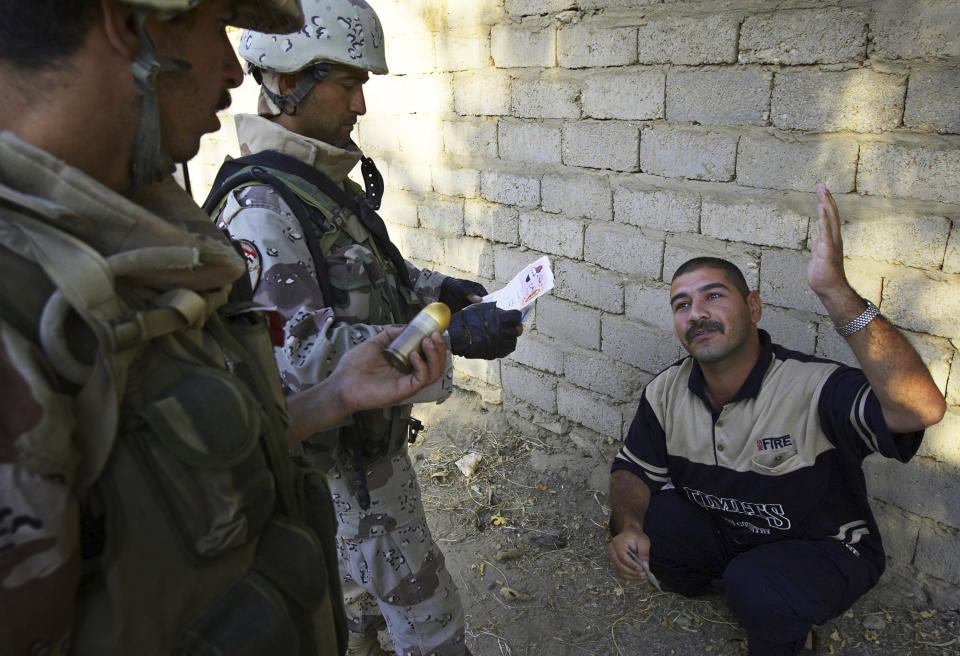 FILE—This file photo from Aug. 6, 2005 shows Iraqi soldiers working with Lima Company of the U.S. Marines 3rd Battalion, 25th Regimen from Ohio, question a man they think might be involved in the killing of U.S. Marines earlier in the week, in Parwana, near Haditha, Iraq. Days before, a nearby roadside bomb killed 14 Marines, many from Lima Company, and a civilian interpreter on August 3, 2005. Some survivors and families of those killed had planned a 15-year reunion this weekend, but it had to be canceled amid restrictions for the COVID-19 pandemic. (AP Photo/Jacob Silberberg, File)