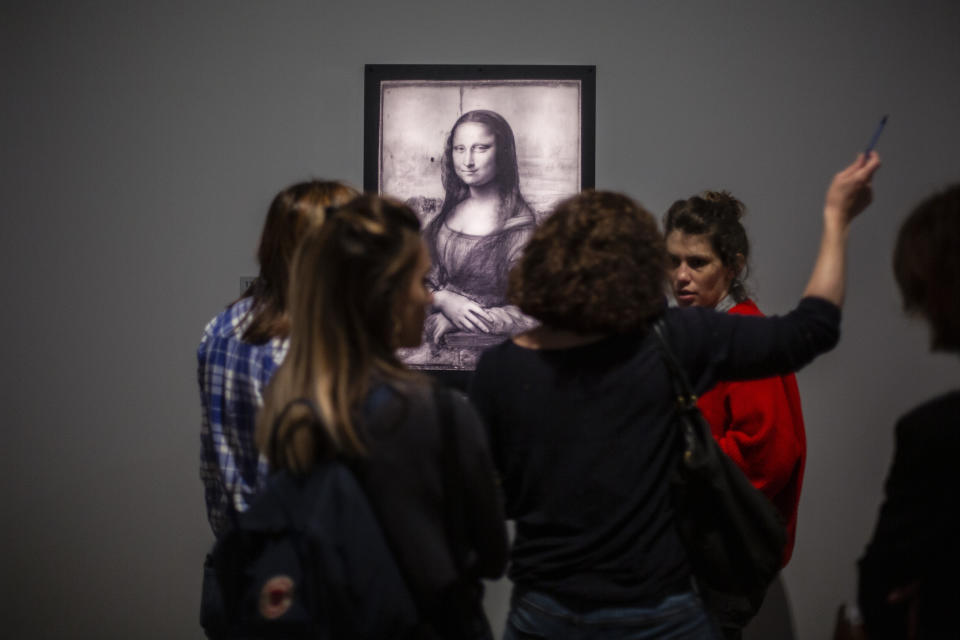 Journalists gather near a Mona Lisa image by Leonardo da Vinci during a visit at the Louvre museum Sunday, Oct. 20, 2019 in Paris. A unique group of artworks is displayed at the Louvre museum in addition to its collection of paintings and drawings by the Italian master. The exhibition opens to the public on Oct.24, 2019. (AP Photo/Rafael Yaghobzadeh)