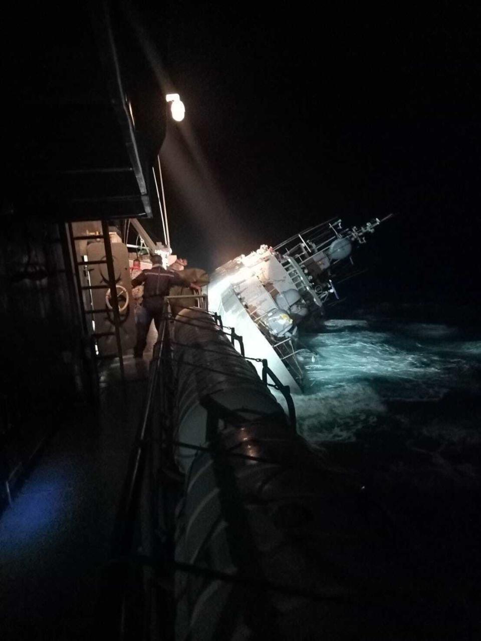 In this photo provided by the Royal Thai Navy, the HTMS Sukhothai corvette leans on its side off the coast of Prachuap Khiri Khan province, Thailand on Sunday, Dec. 18, 2022. The Thai navy ship sunk in the Gulf of Thailand and ships and helicopters were working Monday to rescue sailors from the water. (Royal Thai Navy via AP)