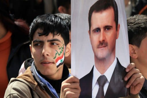 A Syrian demonstrator holds a portrait of President Bashar Al-Assad during a pro-regime rally in Damascus