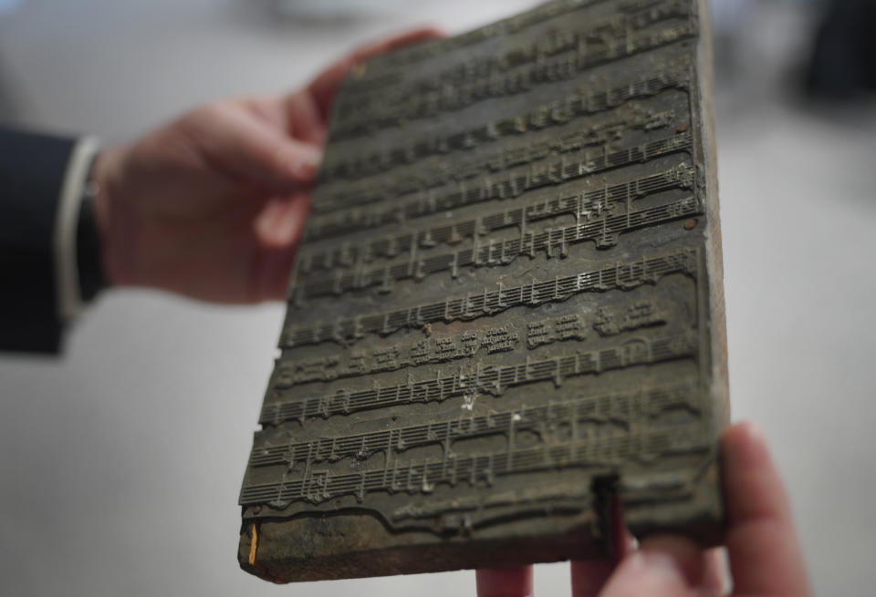 Christopher Lynch, music historian and project coordinator with the Center for American Music at the University of Pittsburgh, holds a printing plate that gospel composer and publisher Charles Henry Pace used to print sheet music, on Tuesday, Feb. 28, 2023, at the University of Pittsburgh, in Pittsburgh. The plate is part of a larger archive owned and housed by the university. (AP Photo/Jessie Wardarski)