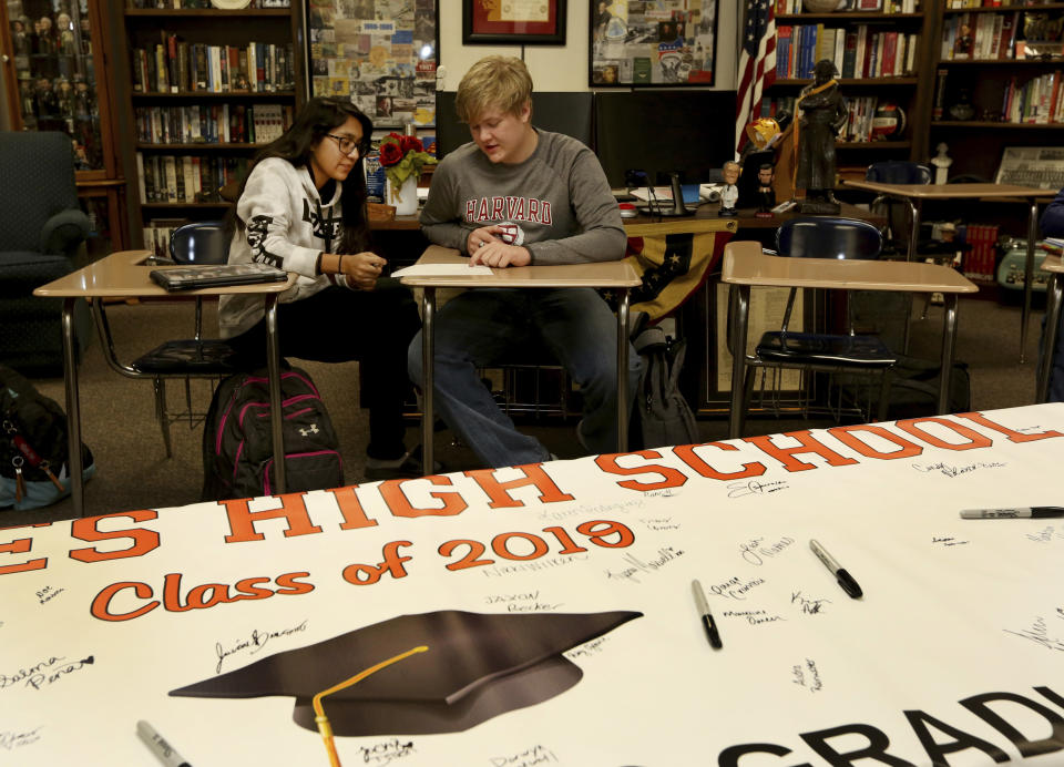 Government class students Alejandra Corral, left, and Braxton Moral work on calculating the estimated cost of living expenses as part of a talk about students who graduate high school making on average more money than non-graduates, at Ulysses High School in Ulysses, Kan., on Wednesday, Dec. 12, 2018. (Sandra J. Milburn/The Hutchinson News via AP)