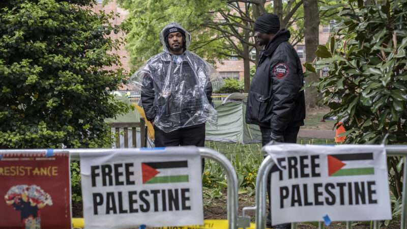 Two security guards stand near "Free Palestine" signs as a protest