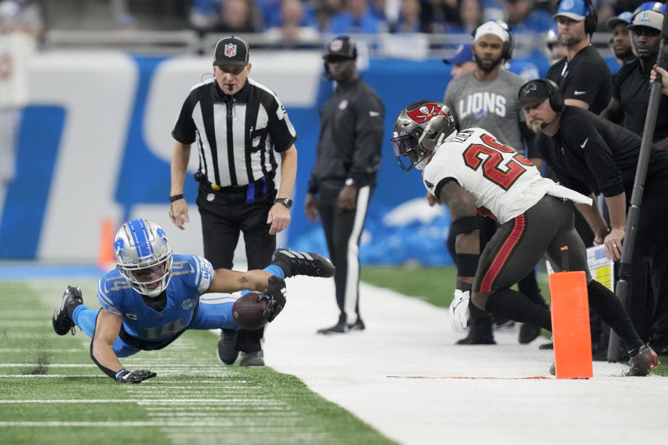 Detroit Lions wide receiver Amon-Ra St. Brown, left, dives for a first down as Tampa Bay Buccaneers safety Christian Izien (29) looks on during the first half of an NFL football NFC divisional playoff game, Sunday, Jan. 21, 2024, in Detroit. (AP Photo/Paul Sancya)