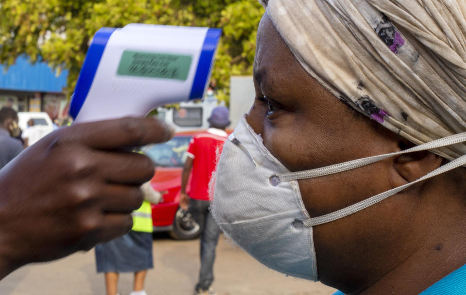 A woman wearing face masks to protect against coronavirus, has her temperature checked by a security personnel before entering a grocery shop at Tembisa township in Johannesburg, South Africa, Tuesday, May 19, 2020. (AP Photo/Themba Hadebe)