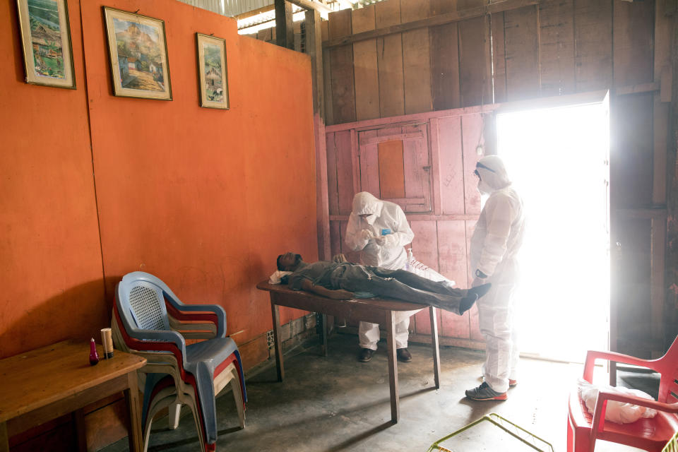 Members of the humanitarian corpse collection team test Daniel Sevillano who was found dead outside his house, for the COVID-19 virus, inside his home in Iquitos, Peru, Monday, March 22, 2021. The pandemic has hit Peru hard, and Iquitos is struggling -- to date, the country has seen more 52,000 deaths, 3,200 of them in Iquitos, a city of half a million people. (AP Photo/Rodrigo Abd)