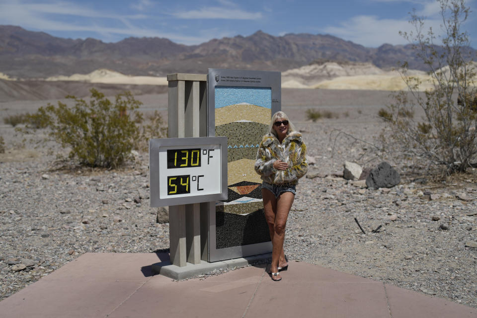 A woman poses by a thermometer, Sunday, July 16, 2023, in Death Valley National Park, Calif. The thermometer is not official but is a popular photo spot. Death Valley's brutal temperatures come amid a blistering stretch of hot weather that has put roughly one-third of Americans under some type of heat advisory, watch or warning. (AP Photo/John Locher)