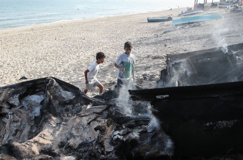 Palestinians inspect boats damaged in Israeli fire, in Rafah in the southern Gaza Strip