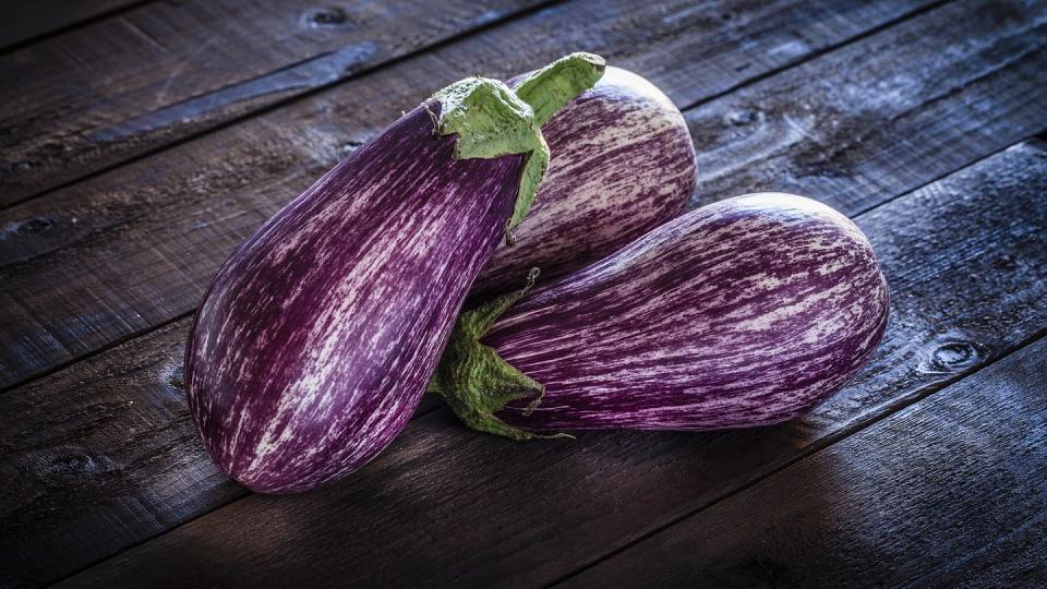 Fresh organic eggplants on crumpled brown paper still life