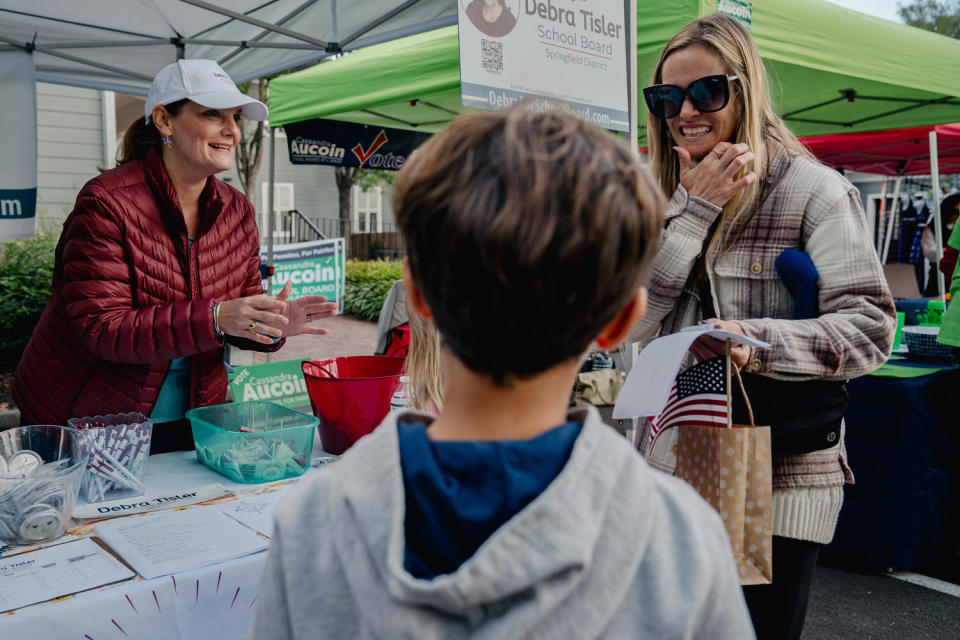 Debra Tisler, left, chats with a mother at her booth at the Clifton Day Festival in Clifton, Va., on Oct. 8, 2023.  (Shuran Huang for NBC News)