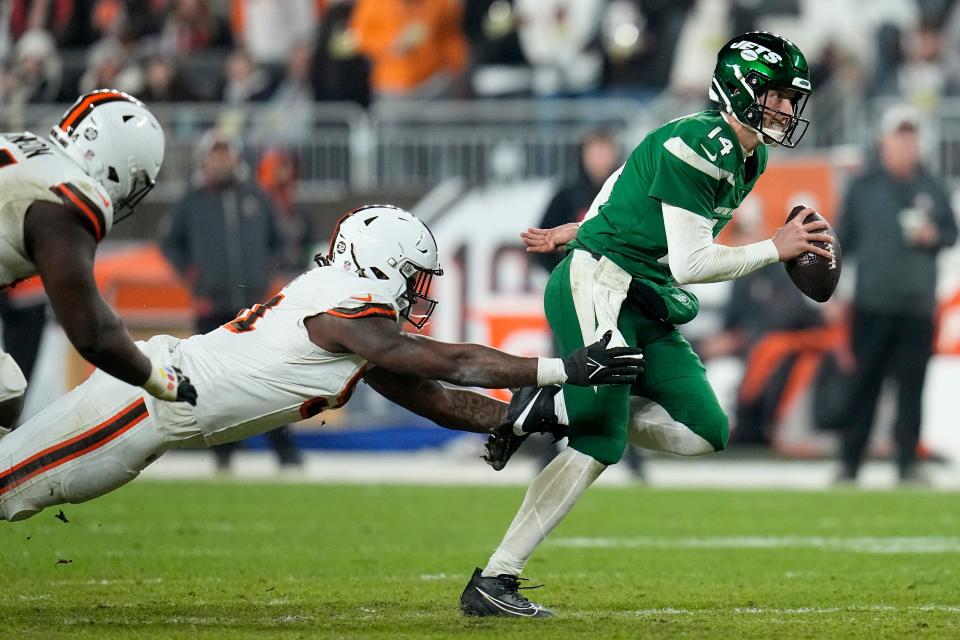 New York Jets quarterback Trevor Siemian breaking way from Cleveland Browns defensive end Alex Wright during the second half of an NFL football game Thursday, Dec. 28, 2023, in Cleveland. (AP Photo/Sue Ogrocki)
