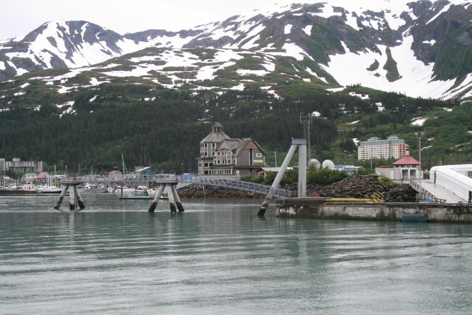 This photo taken July 9, 2012, shows the tiny community of Whittier, Alaska, where most of the 180 year-round residents live in the tall condo in the back, a former Army garrison. Most cruise ship passengers leave for Anchorage once their ships dock in Whittier, but those who stay can kayak, hike trails or visit a few tourist shops, cafes and restaurants. (AP Photo/Mark Thiessen)