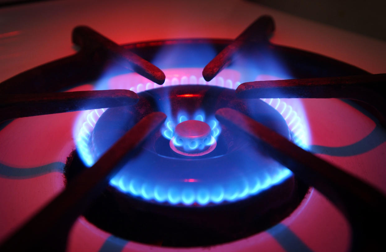 Blue flames rise from the burner of a natural gas stove