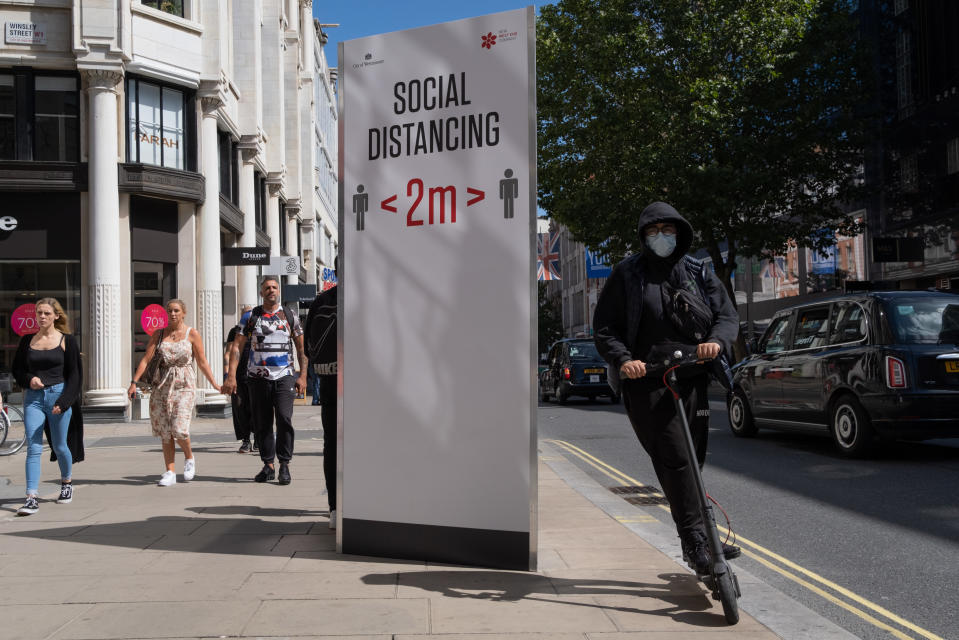 A man riding an eScooter speeds past a social distance board on Oxford Street during the Coronavirus pandemic, on 20th August 2020, in London, England. (Richard Baker / In Pictures via Getty Images)