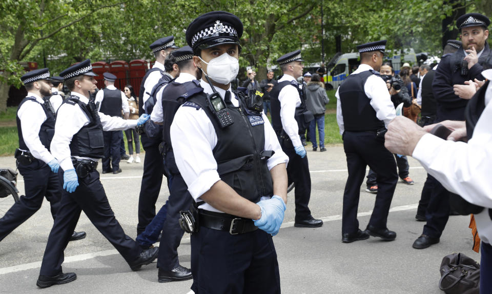 A police officer wears a face mask during a mass gathering protest organised by the group called 'UK Freedom Movement', in Hyde Park in London as the country is in lockdown to help stop the spread of coronavirus, Saturday, May 16, 2020. The group claims that the coronavirus lockdown is illegal. (AP Photo/Kirsty Wigglesworth)