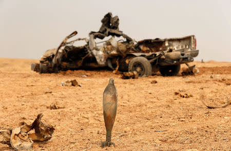 The wreckage of a Kurdish Peshmerga fighters' vehicle, which was destroyed by a roadside bomb explosion, is seen near a shell during a battle with Islamic State militants at Topzawa village, near Bashiqa, near Mosul. REUTERS/Ahmed Jadallah