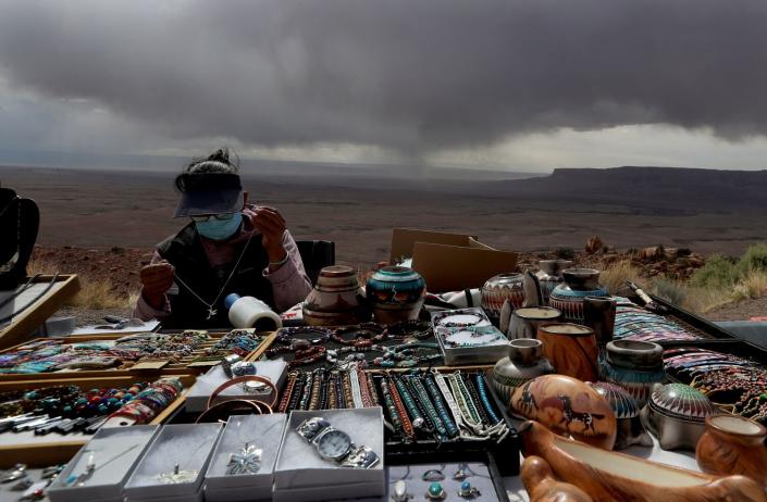 Storm clouds appear threatening but produce little rain as a Native American woman sells handmade jewelry near Page, Ariz.