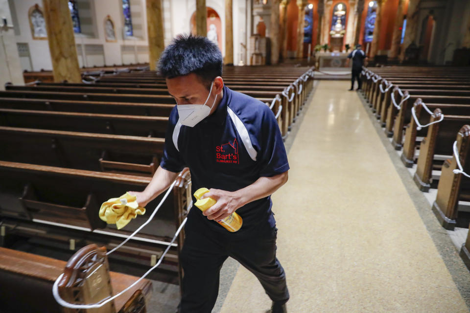 Un empleado de la iglesia San Bartolomeo de Queens, Nueva York, desinfecta la instalación el 6 de julio del 2020, en que la parroquia reabrió sus puertas tras un cierre motivado por el coronavirus. (AP Photo/John Minchillo)