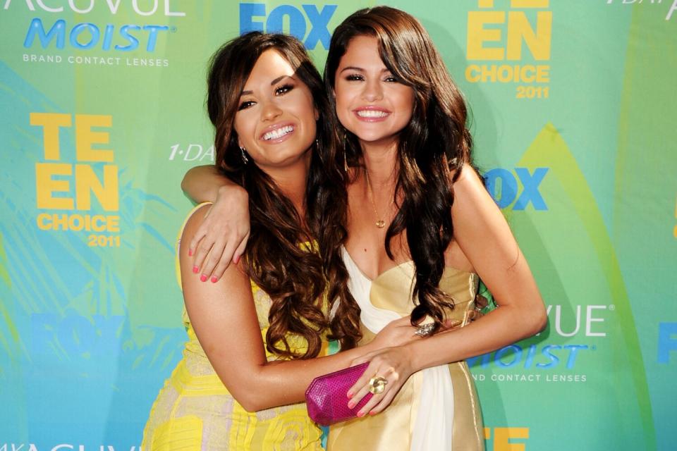 Two young women hug each other and pose for photographs