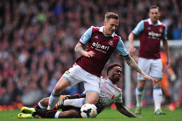 Liverpool's Raheem Sterling (down) fights for the ball with West Ham United's Matthew Taylor during their English Premier League match, at Upton Park in London, on April 6, 2014