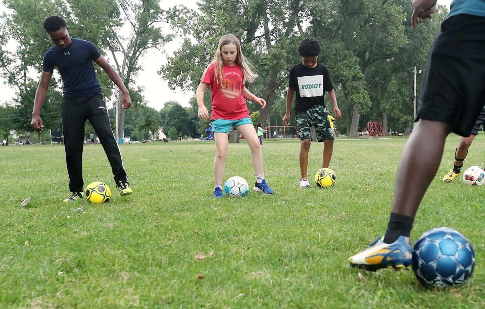 Young aspiring soccer players copy the ball handling techniques of coach Chidozie Martins during the 15th annual free summer soccer camp put on by the Akron Inner City Soccer Club at Hardesty Park in Akron on Monday.