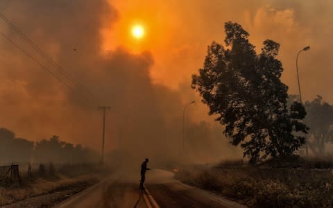 A firefighter tries to extinguish hotspots during a wildfire in Kineta, near Athens - Credit: AFP